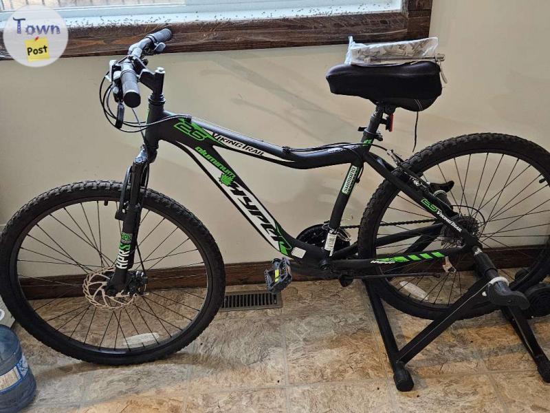 Photo of 21 speed mountain bike, complete with indoor roller system for those who would like to use in doors winter month, this unit complete cost my $750.00 and has never turned a tire. 